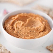 Side photo of a bowl with lentil dip and some crackers around.