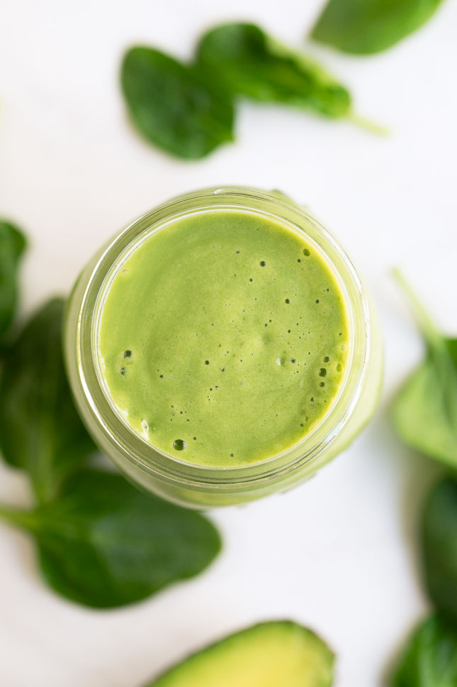 An overhead shot of a glass container of avocado smoothie