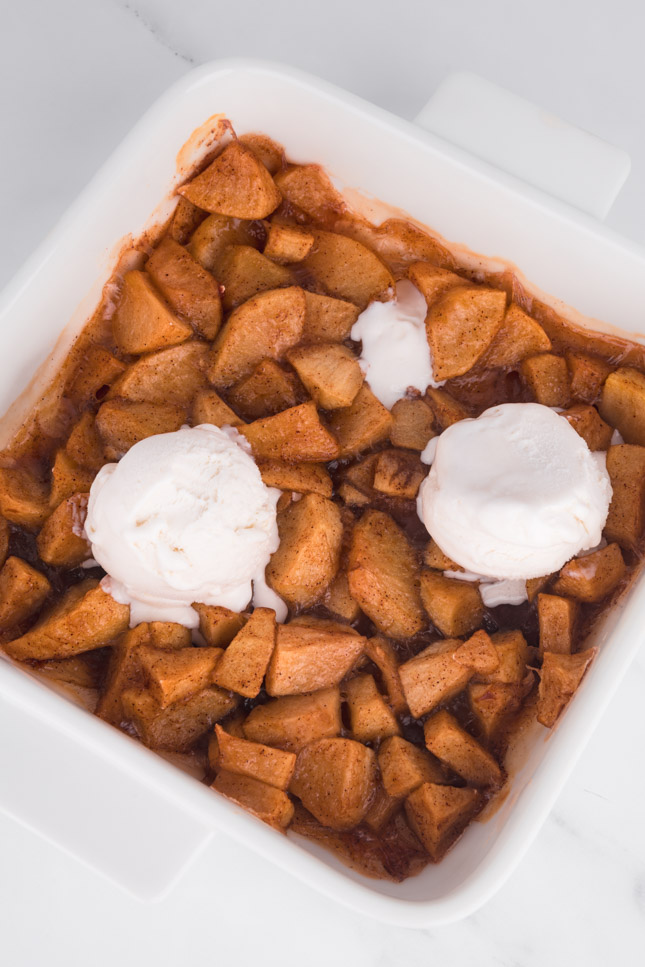 Photo of a baking dish with baked apples and vegan vanilla ice cream