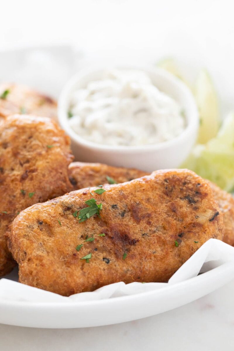 Close-up photo of a dish with beer-battered vegan fish sticks garnished with chopped parsley.