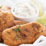 Close-up photo of a dish with beer-battered vegan fish sticks garnished with chopped parsley with a heading.