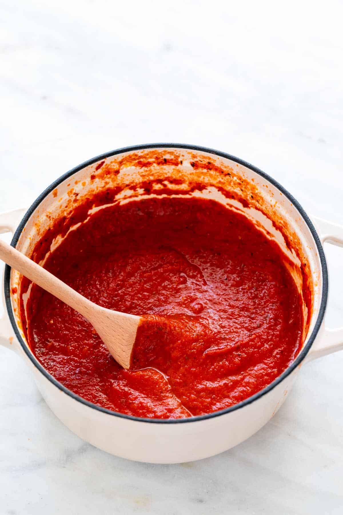 Homemade marinara sauce in a pot with a spoon.