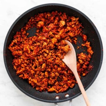 Soyrizo cooking in a skillet with a wooden spoon.