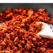 Vegan soy chorizo in a skillet with a wooden spoon.