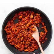 Soyrizo in a skillet, stirred with a wooden spoon.