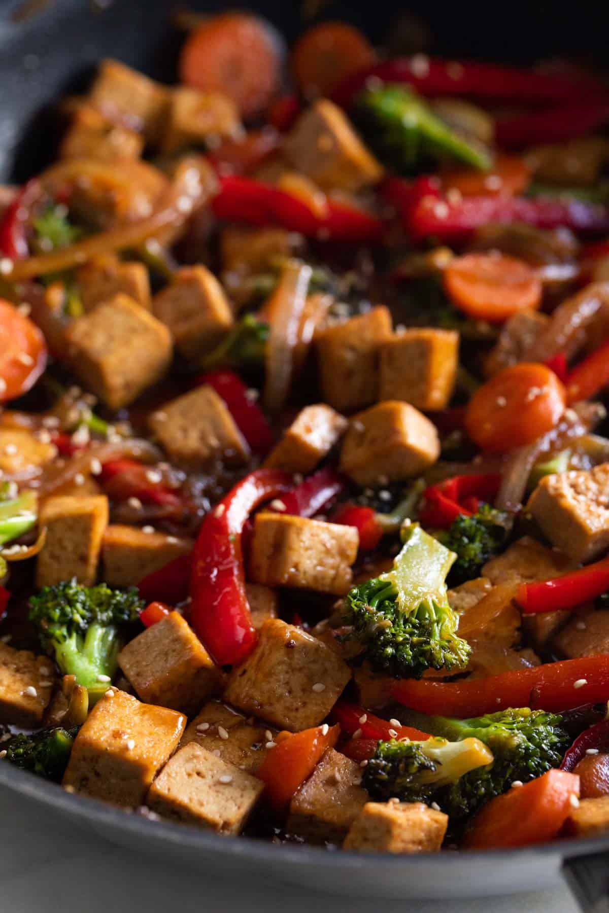 A skillet with tofu stir fry garnished with sesame seeds.