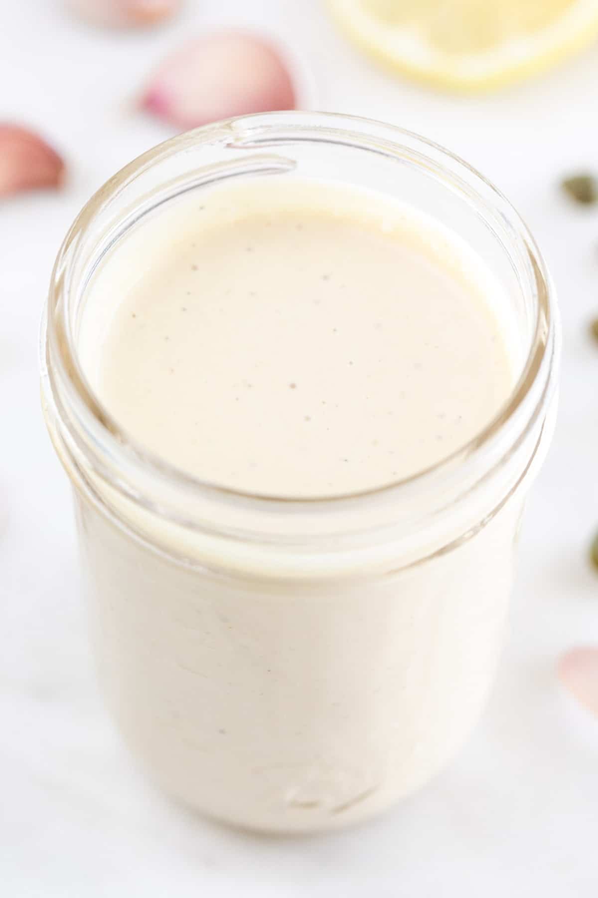 Mason jar filled with vegan Caesar dressing and ingredients in the background.