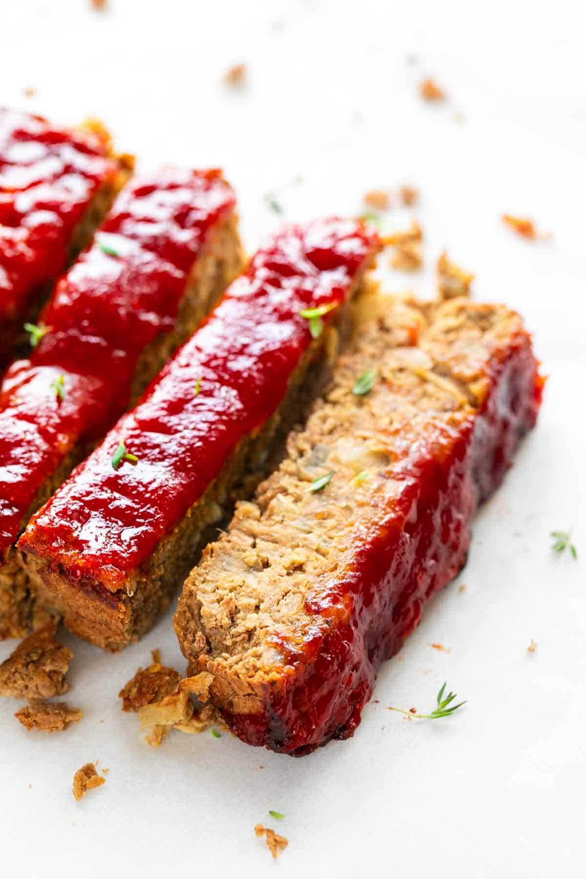 Slices of vegan lentil loaf with fresh oregano on top.