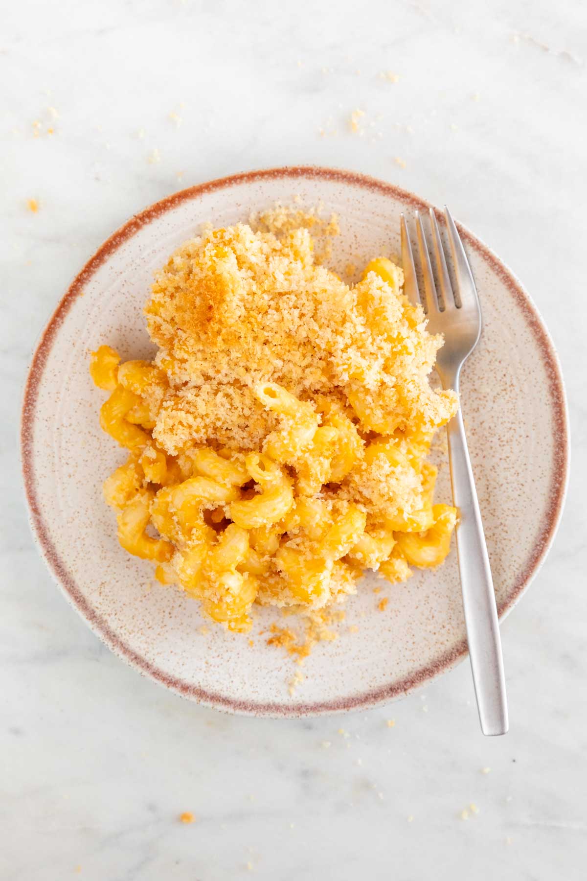 A plate of baked vegan mac and cheese with a fork.