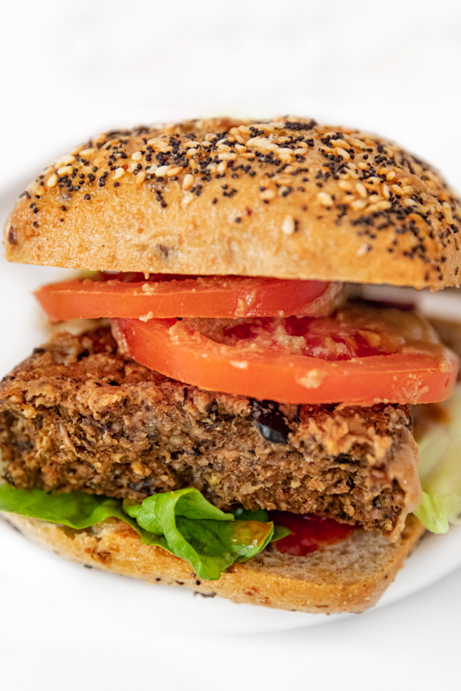 Close-up shot of a black  bean burger with bread and toppings