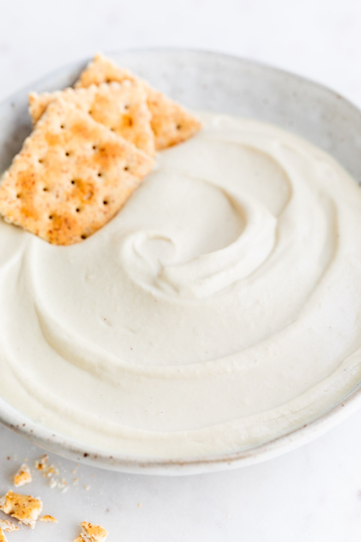 Vegan cashew cheese accompanied by crackers in a bowl.