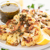 Square close-up photo of cauliflower steak with chimichurri on top