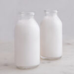 Square photo of two glass bottles of coconut milk