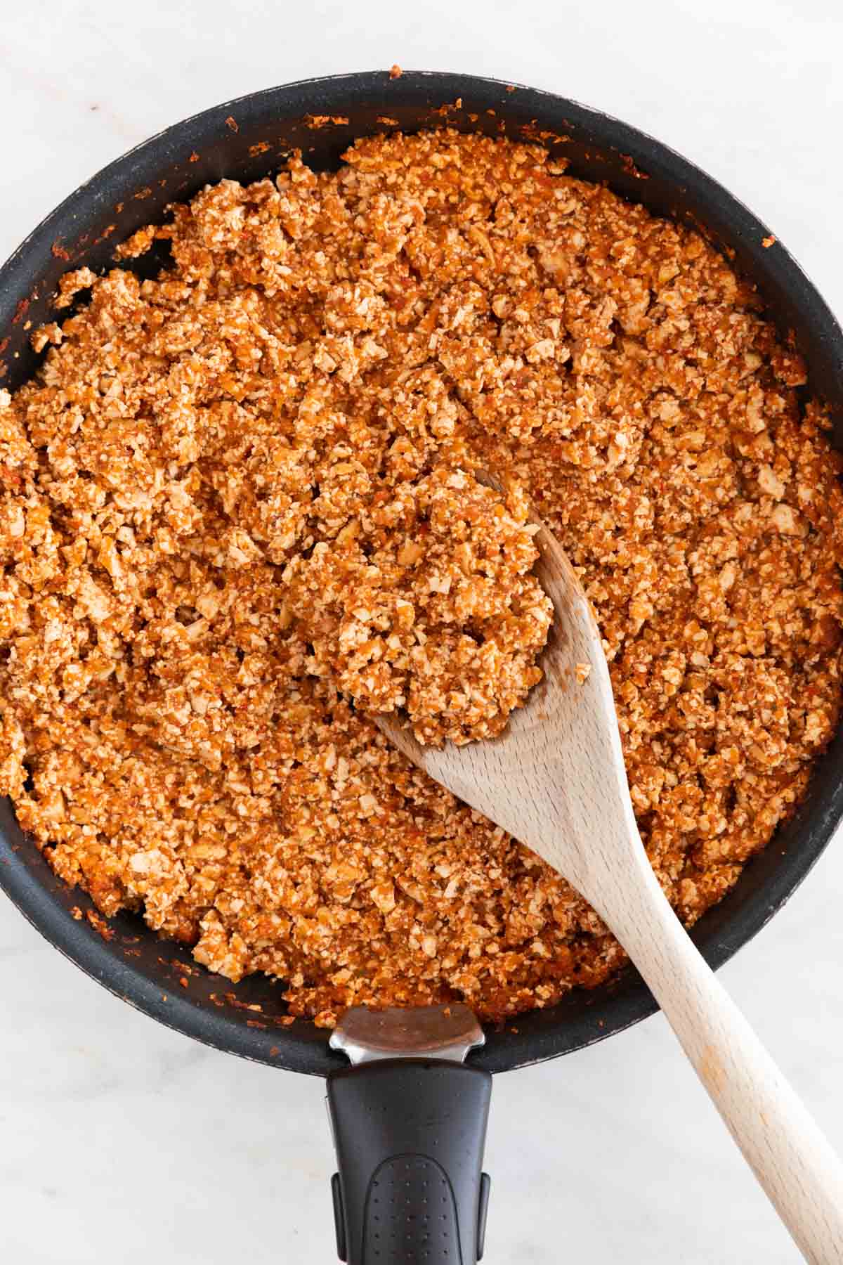 Overview of a frying pan with Chipotle sofritas and a wooden spoon.