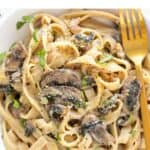 Golden fork resting on a plate of vegan mushroom pasta.