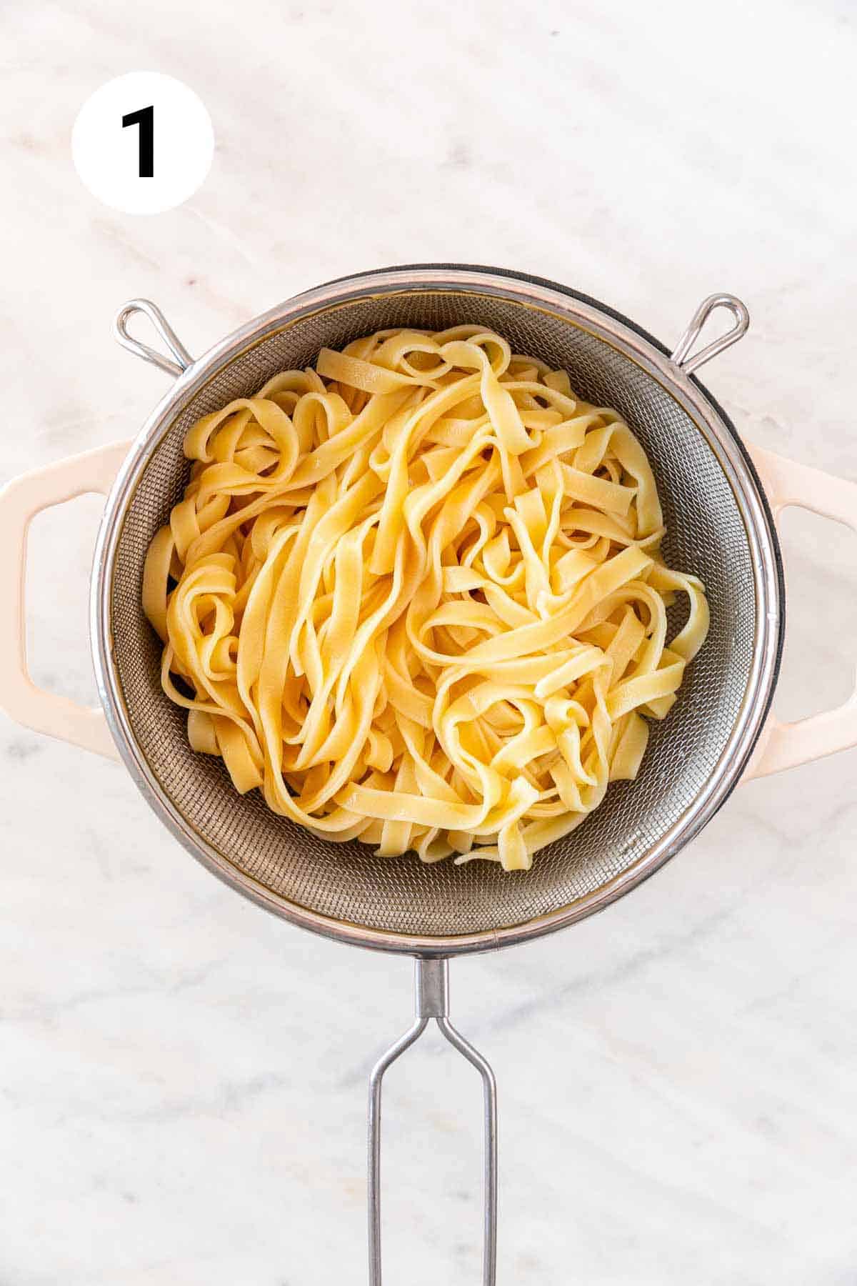 Pasta colander with tagliatelle in a pot.