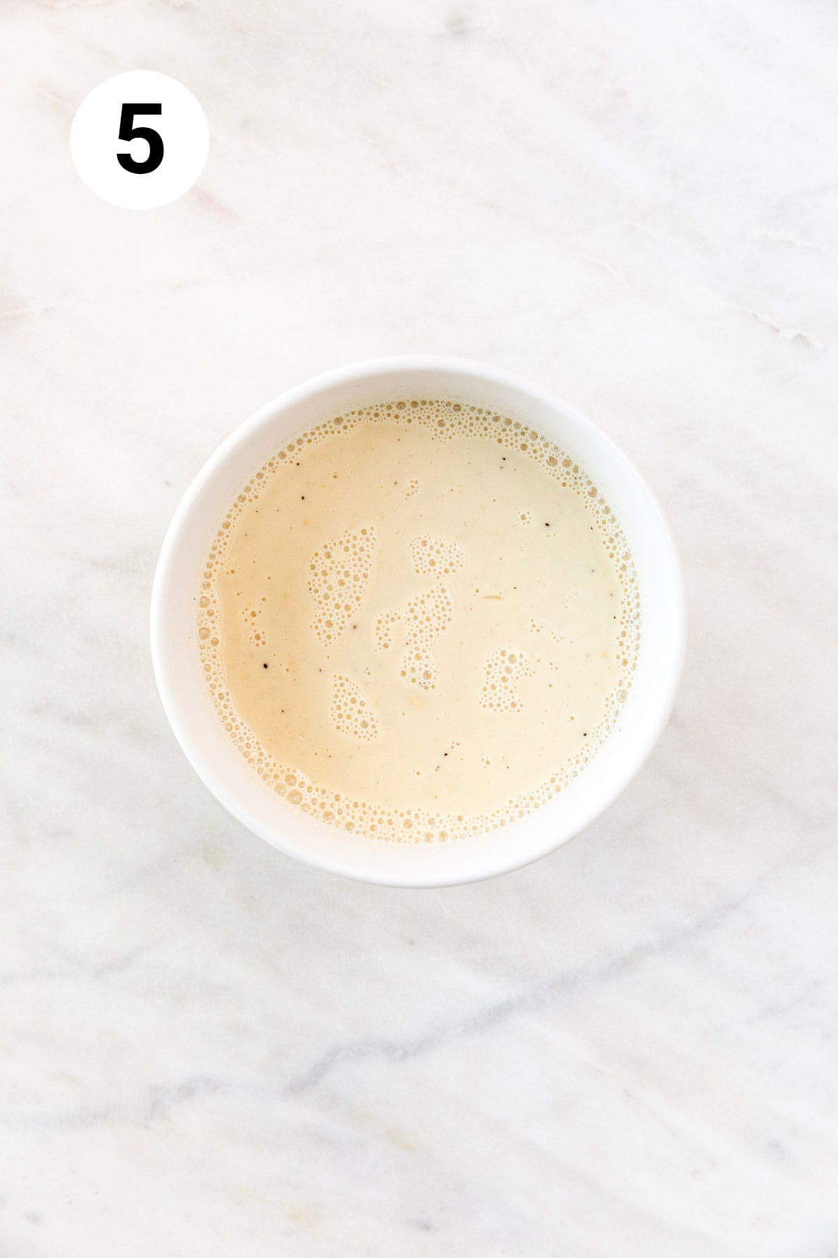 A small bowl with the flour, nutritional yeast, salt, pepper, and milk whisked together.