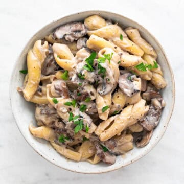 Vegan mushroom stroganoff in a bowl, garnished with fresh parsley and black pepper.