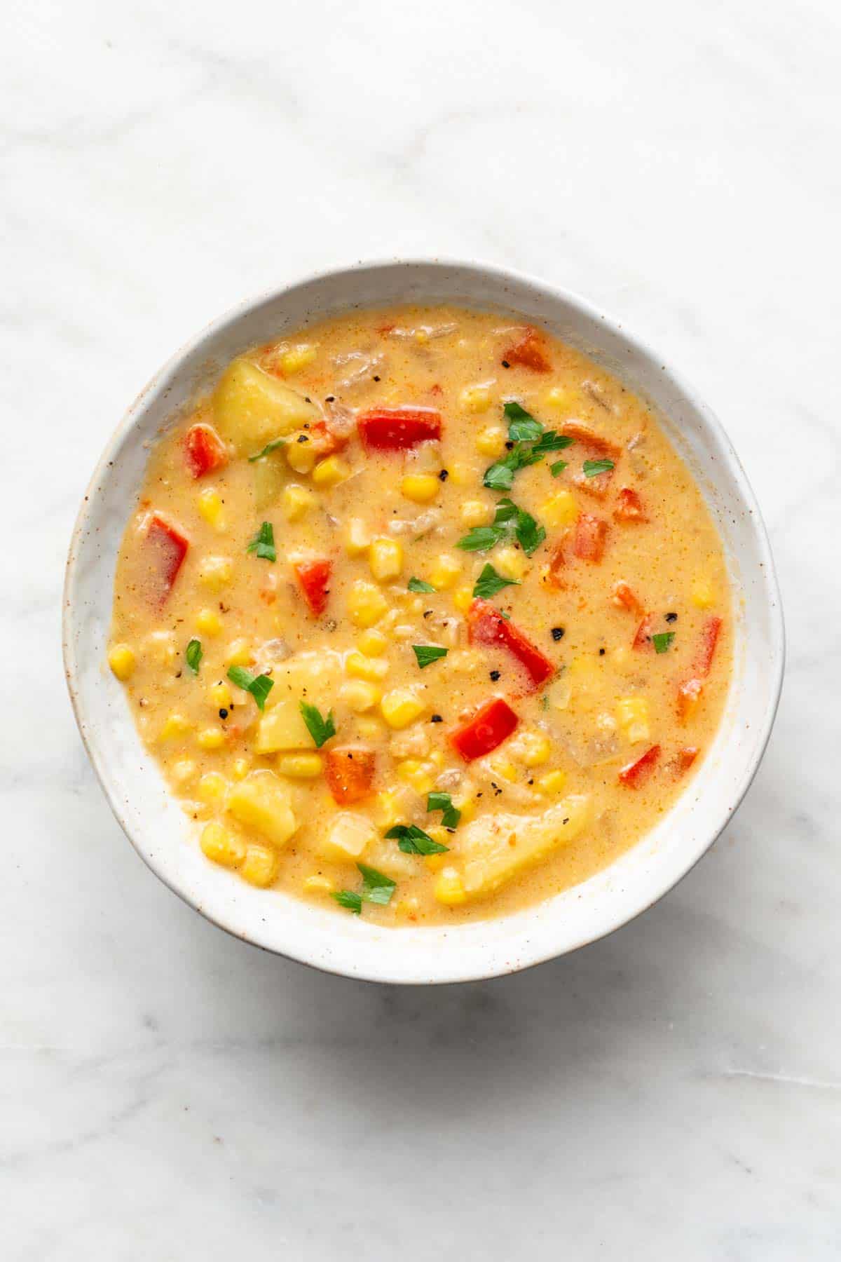 Vegan potato and corn chowder in a bowl garnished with parsley.