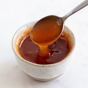 Spoon dipping into a small bowl of homemade sweet and sour sauce.