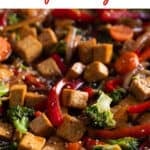 A skillet with tofu stir fry garnished with sesame seeds.