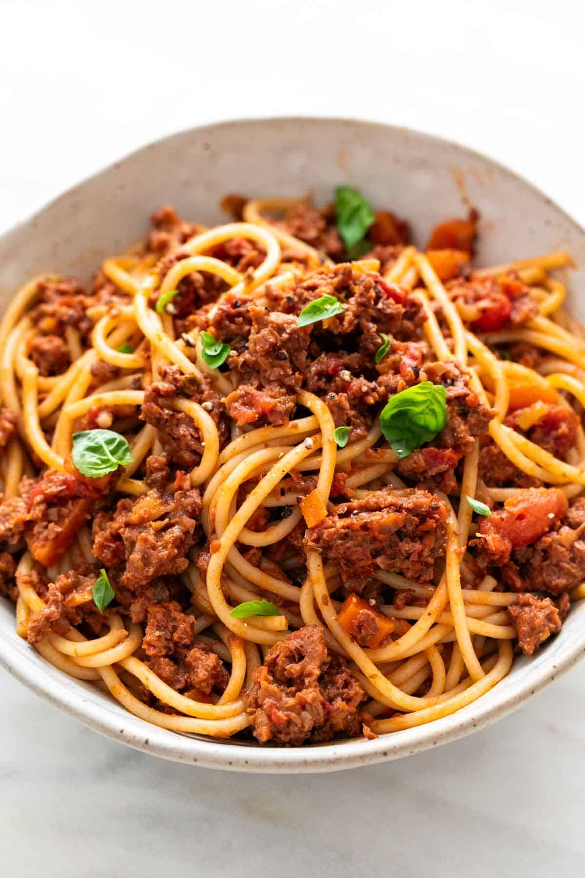 Vegan bolognese spaghetti in a bowl with basil.