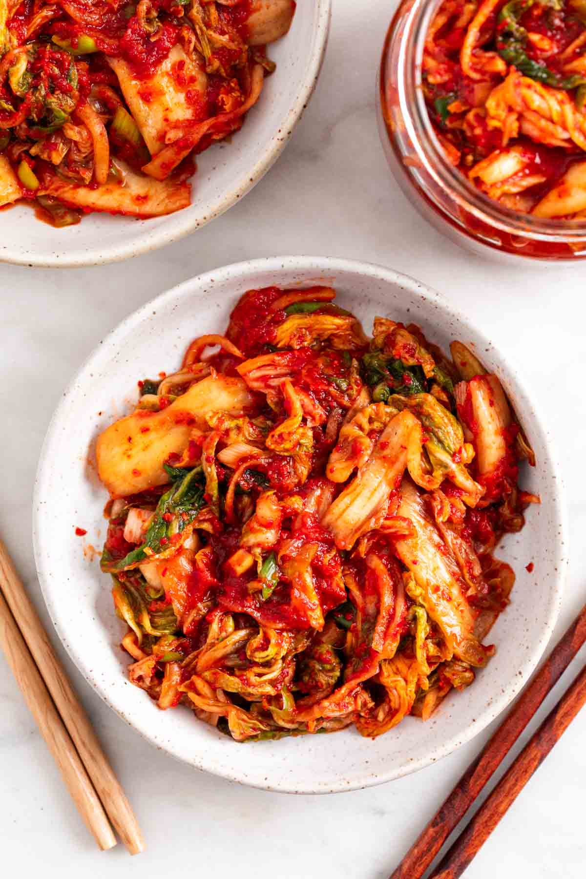 Vegan kimchi in two shallow dishes and a jar.