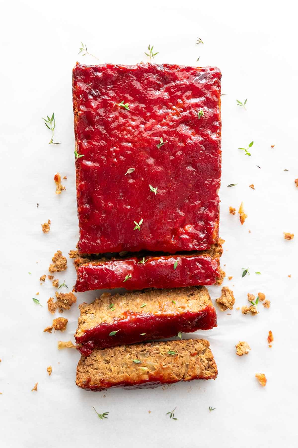 A sliced vegan lentil loaf garnished with fresh oregano.
