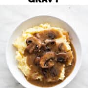 Dish with vegan mashed potatoes and vegan mushroom gravy on a white background.