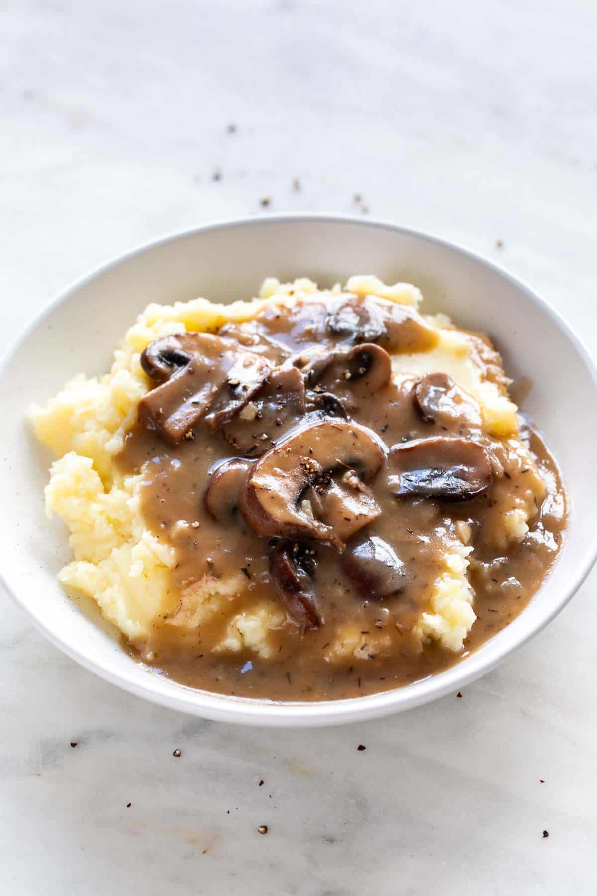 Plate with vegan mushroom gravy over vegan mashed potatoes.