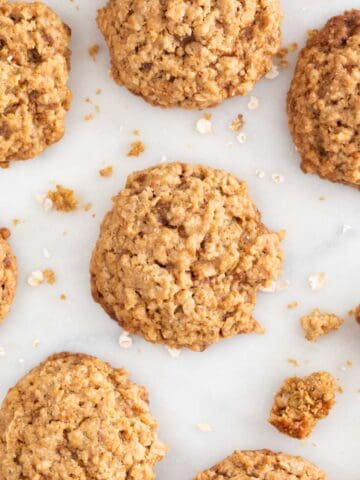 Lots of vegan oatmeal cookies on a marble slab.