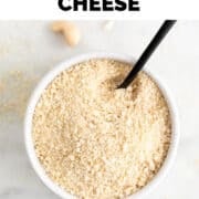 White bowl filled with vegan Parmesan cheese and a spoon.