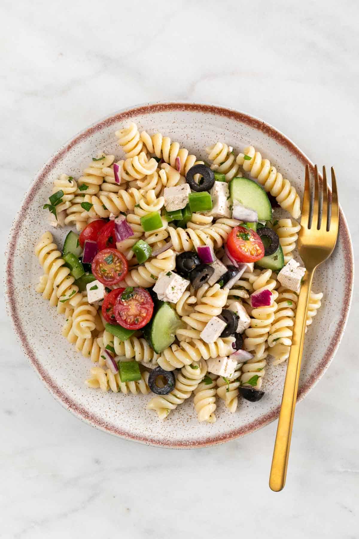 Vegan pasta salad served on a plate with a fork.
