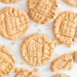 Lots of vegan peanut butter cookies on a marble slab.