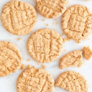 Lots of vegan peanut butter cookies on a marble slab.