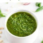 Bowl of vegan pesto with background ingredients.