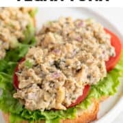 Vegan tuna on bread with lettuce and tomato slices.