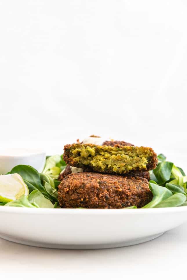 Side shot of a plate of falafel and vegan yogurt sauce