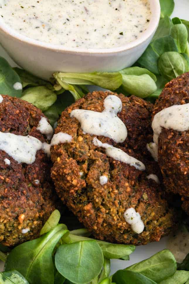 Close-up shot of a plate of falafel with some vegan yogurt sauce on top