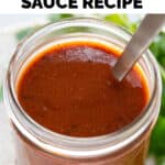Red enchilada sauce jar with a spoon, tortillas, and cilantro placed around it.