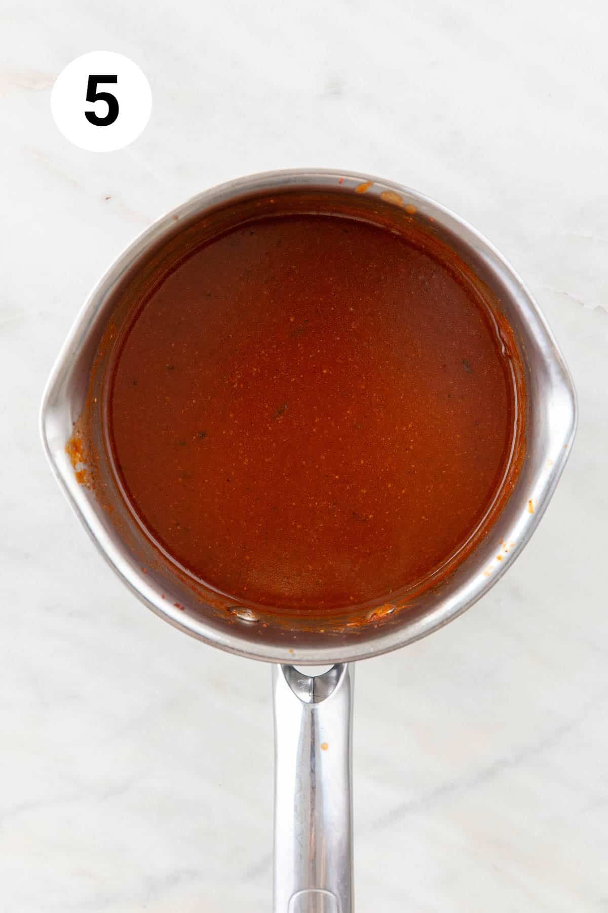 Thickened red enchilada sauce in a saucepan.