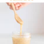 A spoon lifting some flax seed mix from a small container.