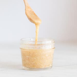 A spoon lifting some flax seed mix from a small container.