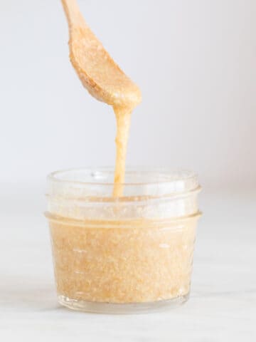 A spoon lifting some flax seed mix from a small container.