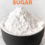Close-up shot of a bowl of powdered sugar with the words how to make powdered sugar
