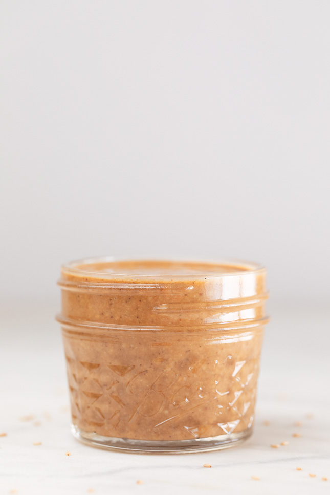 A side shot of a small glass container with homemade tahini