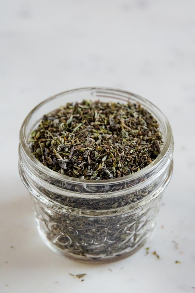 A close shot of a glass jar with homemade Italian seasoning
