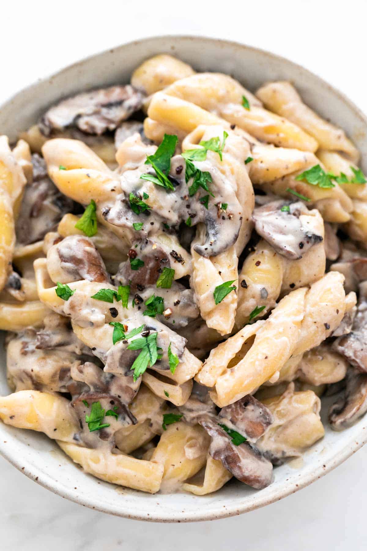 Bowl of vegan mushroom stroganoff garnished with parsley and pepper.