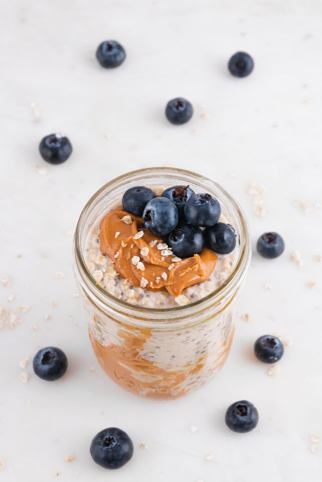 Photo of a glass jar of overnight oats decorated with some blueberries
