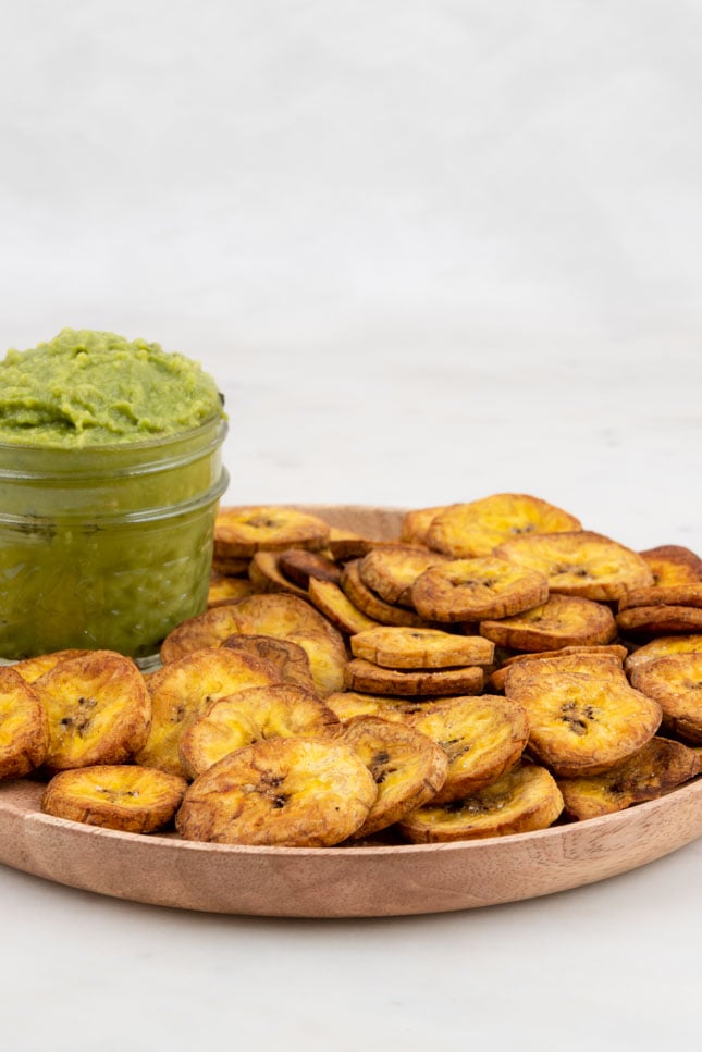 Side shot of a plate of plantain chips with guacamole
